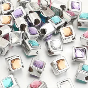 Macro detail of square silver spacer beads with colorful resin gemstone inlays