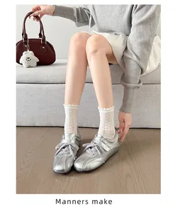 Detailoverzicht van zilveren satijnen ballet sneakers met klittenband en linten
