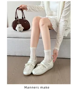 Detailopname van witte satijnen ballet sneakers met klittenband en kanten sokken