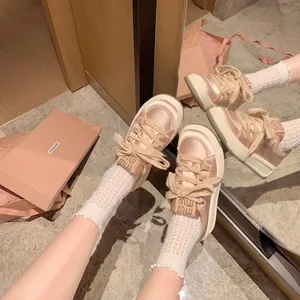 Elegantes zapatillas de plataforma en satén crema con cordones de cinta y suelas gruesas