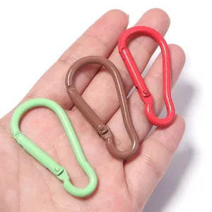 Primo piano dettagliato di tre moschettoni colorati in alluminio a forma di cuore in mano