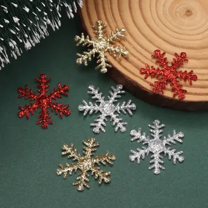 Vista macro detallada de parches de copos de nieve brillantes en oro, rojo y plata para Navidad