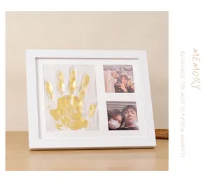 Close-up view of a white DIY keepsake picture frame featuring a golden handprint and photos