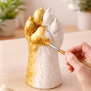 Detail showing the DIY process of painting a plaster pet paw memorial model in gold