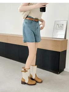 Retro patchwork Western cowboy boots with foldable shaft worn in a stylish indoor setting.