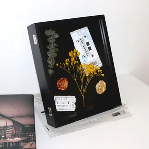Vista detallada de un marco de caja de sombra 3D negro con flores y tickets retro
