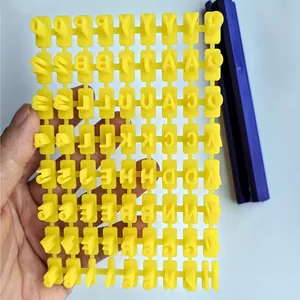 Detailed view of yellow alphabet and number stamps for pet paw print memorial kit.