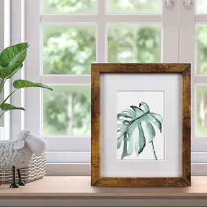 Vue détaillée d'un cadre photo en bois rustique avec aquarelle de feuille de monstera