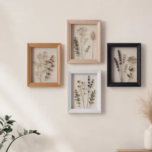 Vista detallada de cuatro marcos de madera huecos con flores secas en una pared beige