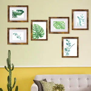 Jeu de cadres photo artisanaux en bois sur un mur vert clair dans un salon chaleureux