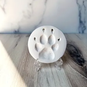 Detailed view of a pet paw print impression on a white memorial circular clay disc