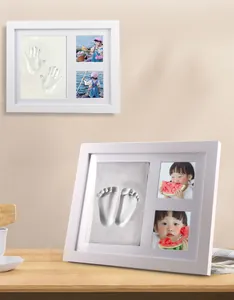 Close-up of white baby handprint and footprint clay keepsake photo frame on a table