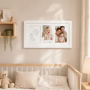 Elegant white nursery keepsake frame with baby handprint clay and family photos on wall.