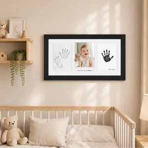 Nursery wall decor featuring a black baby handprint and footprint souvenir photo frame