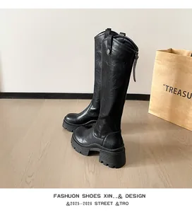 Close-up detail of black platform knight boots featuring chunky heels and side zippers