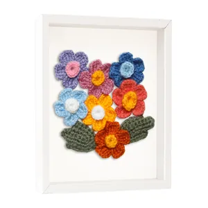 Vue détaillée d'un cadre vitrine blanc avec des fleurs colorées au crochet