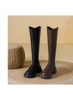 Two pairs of stylish chunky heel knight boots in black and brown on a woven round rug