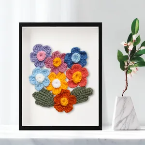 Vue détaillée de fleurs colorées au crochet faites main dans un cadre boîte noir carré.
