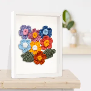 Détail de fleurs au crochet colorées dans un cadre carré creux blanc en relief 3D.