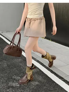 Retro patchwork western cowboy boots styled with a brown leather handbag outdoors