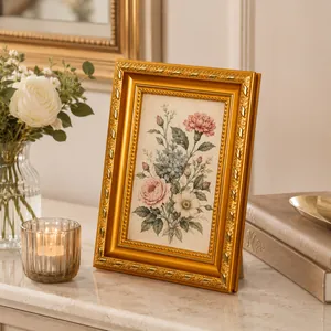 Elegante marco de fotos dorado vintage con ilustración floral sobre una mesa de mármol.