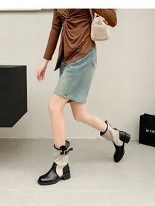 Detailed side view of retro patchwork western cowboy boots worn by a model walking.