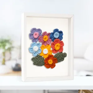Cadre vitrine blanc avec des fleurs colorées faites main au crochet et feuilles.