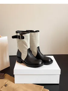 Macro view of bicolor retro western boots featuring black leather and beige canvas contrast.