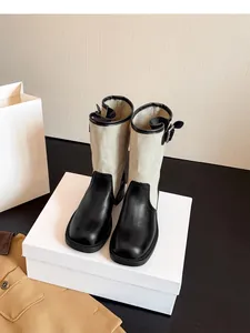 Detailed view of vintage patchwork western cowboy boots with buckle on a white box