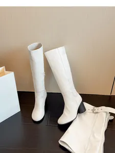 Detailweergave van witte afneembare kniehoge laarzen met beenkap en gesp op de vloer