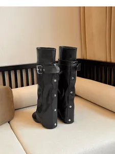 Detailopname van zwarte leren laarzen met broekspijp-stijl, studs en gespdetails.