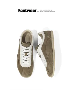 Macro view of vintage olive brown suede sneakers with white laces and thin rubber soles.