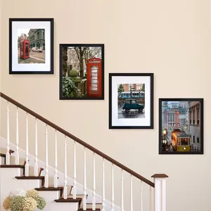 Set of black PVC photo frames with white mats arranged in a gallery wall on a staircase.