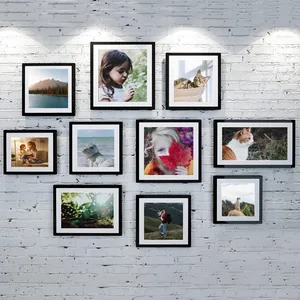 Gallery wall display of black PVC picture frames with white mats on a white brick wall