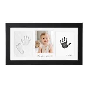 Detail view of a black DIY baby hand and footprint photo frame with clay imprints