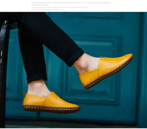Detailed close-up showing texture and stitching of yellow leather slip-on loafers for men.