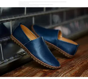 Close-up of blue textured leather slip-on loafers with brown stitched rubber soles.