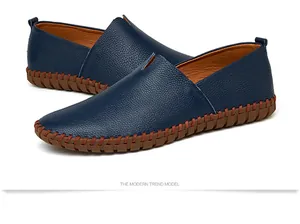 Detailed view of navy blue grain leather slip-on loafers with brown stitched sole