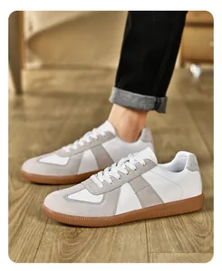 Vista dettagliata delle sneakers retrò German Army Trainer bianche con camoscio grigio.