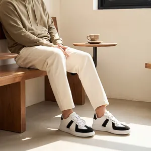 Hoogwaardige casual Duitse leger trainers in zwart en wit, gedragen door iemand in een café