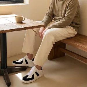 Close-up van zwart-witte GAT-sneakers gedragen door iemand in een gezellige café-setting.