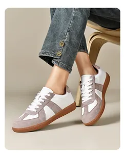 Primo piano di sneakers GAT vintage bianche e grigie indossate con jeans