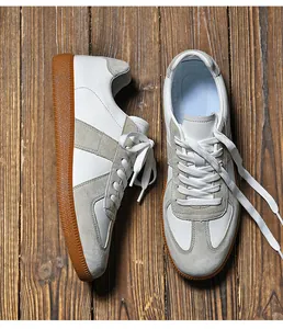 Dettaglio macro di sneaker GAT vintage in pelle bianca e camoscio grigio su legno