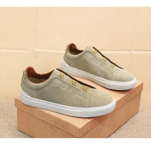 Dettaglio di eleganti mocassini da uomo in pelle scamosciata verde con suola bianca.