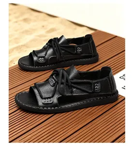 Detailopname van zwarte leren vetersandalen voor heren op een houten terrasvloer.