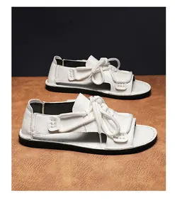 Witte casual herensandalen met touwdetail op een bruine lederen achtergrond foto