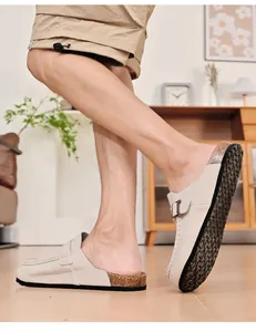 Seitenansicht beiger Herren-Mules an den Füßen in einem sehr gemütlichen Wohnzimmer