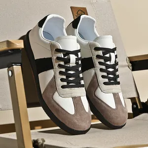 Dettaglio ravvicinato di sneaker GAT retrò bianche e grigie su sedia pieghevole