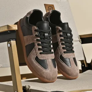 Dettaglio ravvicinato delle sneakers rétro German Army Trainer in pelle nera e camoscio marrone