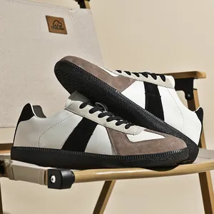 Sneaker retrò dell'esercito tedesco in pelle bianca e camoscio marrone su una sedia